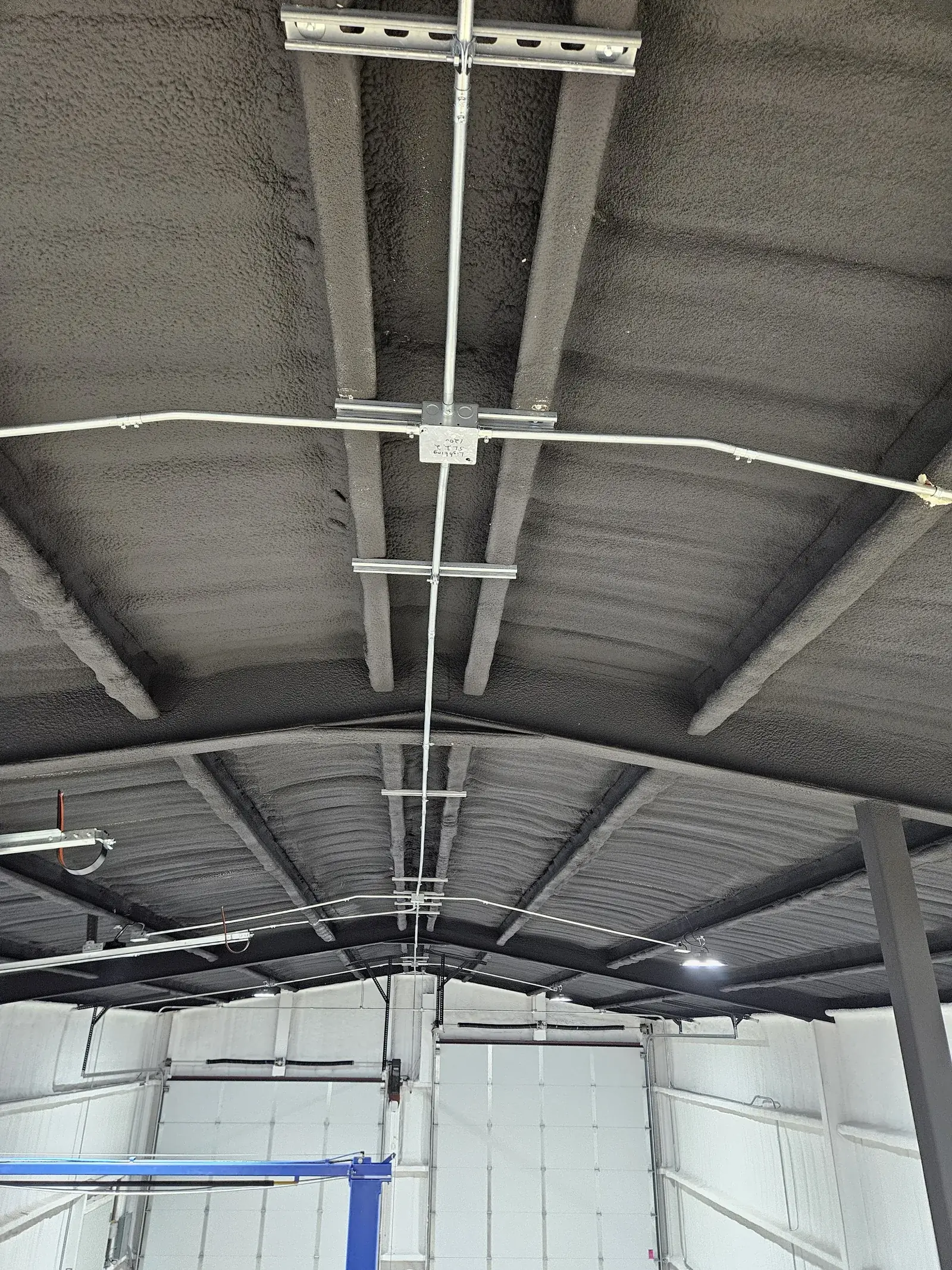Steel conduit T-junction at ceiling ridge in metal building